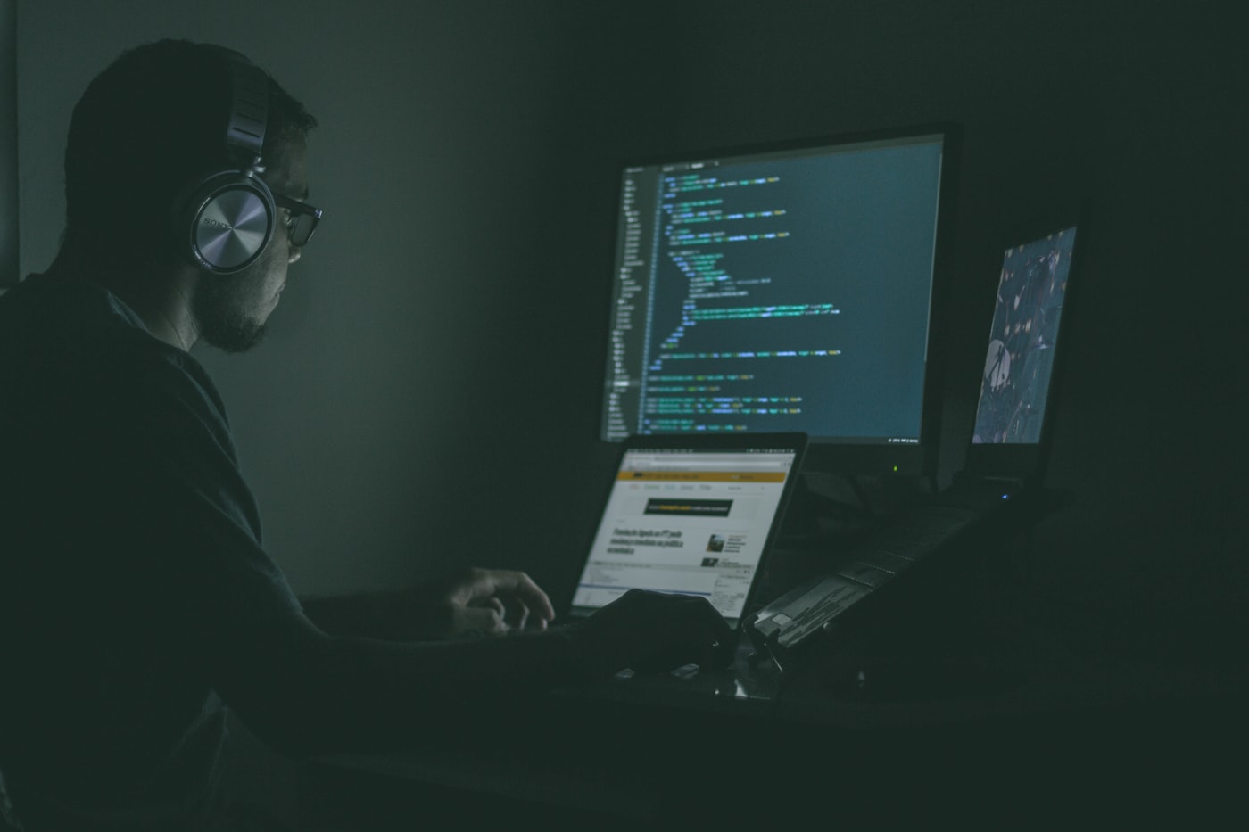 Cyber security analyst working at a laptop in the dark